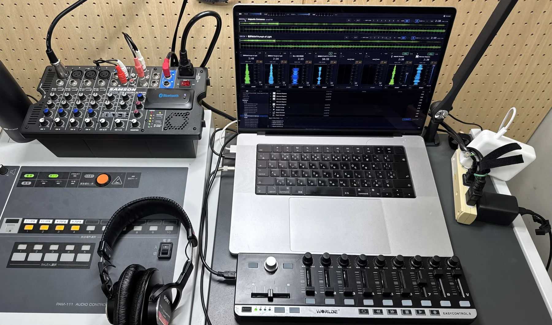 会場の放送設備の隣に、ミキサー、MacBook、MIDIコントローラー、ヘッドホンを並べた当日の卓まわり。MacBookの画面にOctaQが表示されている